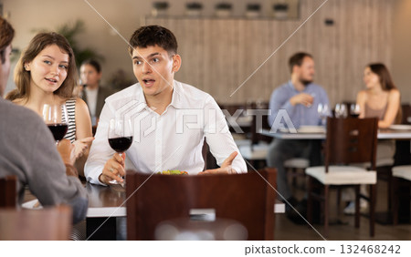 Couple and adult man eating and talking in restaurant 132468242