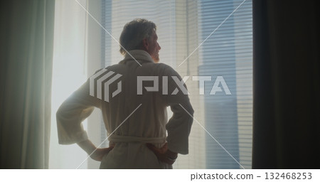 Mature Man Looks Out Window, Pulls Back Heavy Curtains, and Stretches Mature Man Looks Out Window, Pulls Back Heavy Curtains, and Stretches 132468253