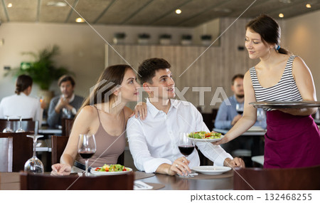 Waitress brings order to young man and woman couple Waitress brings order to young man and woman couple 132468255
