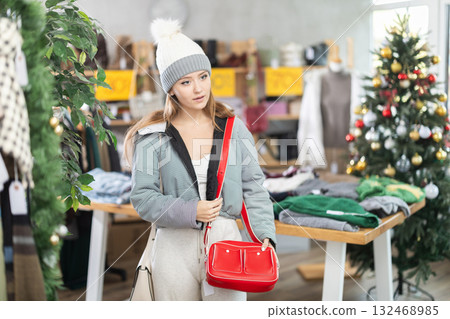 Young woman in hat choosing a red handbag Young woman in hat choosing a red handbag 132468985