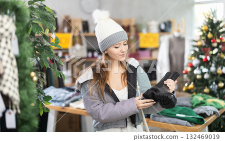 Girl client looks at products in store, looks closely at platform boots, picks up wardrobe item Girl client looks at products in store, looks closely at platform boots, picks up wardrobe item 132469019