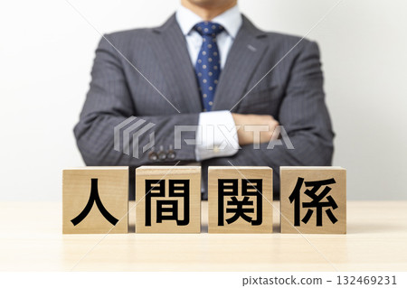 A businessman with his arms crossed and a block that reads "Human Relationships" 132469231