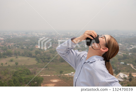 Asian businesswoman wearing N95 mask for protect Bad air pollution (PM2.5) covered Chiang Rai province, Thailand. PM2.5 levels meaning the air quality posed a health hazard. 132470039