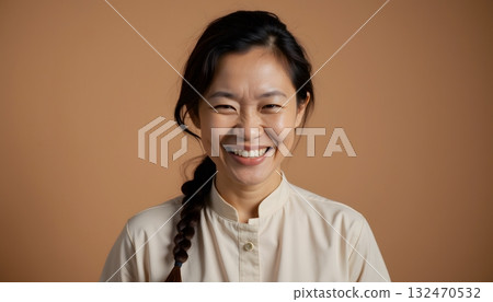 Joyful Woman with Dark Hair Sporting a Braid and a Beige Blouse Against a Neutral Background 132470532