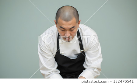 Professional male chef preparing ingredients in kitchen with focused expression 132470541