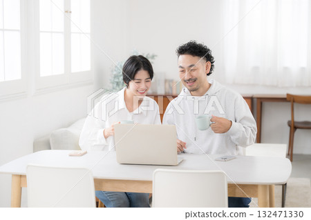A couple talking while looking at a dining computer in a beautiful living room. An image of a happy marriage A couple talking while looking at a dining computer in a beautiful living room. An image of a happy marriage 132471330