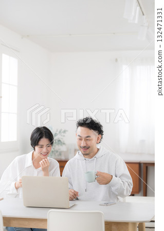 A couple talking while looking at a dining computer in a beautiful living room. An image of a happy marriage A couple talking while looking at a dining computer in a beautiful living room. An image of a happy marriage 132471331