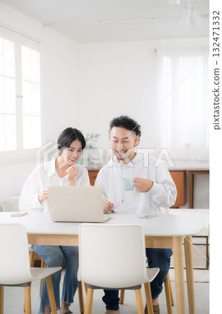 A couple talking while looking at a dining computer in a beautiful living room. An image of a happy marriage A couple talking while looking at a dining computer in a beautiful living room. An image of a happy marriage 132471332