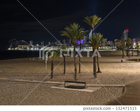quiet night beach, still beachside beneath shimmering night sky with soft moon and city illumination quiet night beach, still beachside beneath shimmering night sky with soft moon and city illumination 132471515