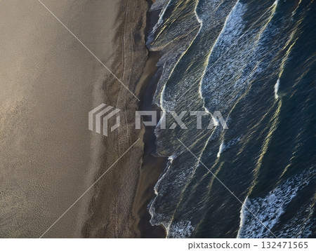 bright waves with stormy reflections, nighttime shoreline with shimmering water and dynamic surf 132471565