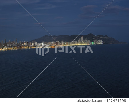 nighttime coastal scene, distant lighthouse illumination over calm waters with vibrant harbor lights nighttime coastal scene, distant lighthouse illumination over calm waters with vibrant harbor lights 132471598