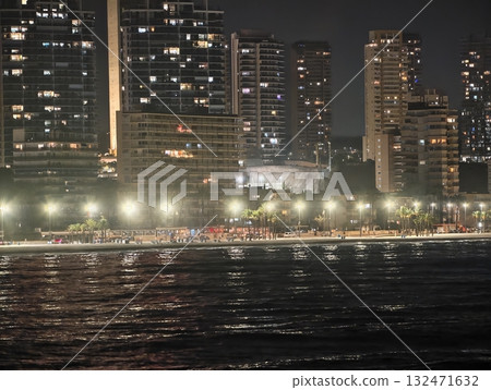 enchanting dusk beside bright oceanfront, beautiful evening with calm waves and tall buildings afar enchanting dusk beside bright oceanfront, beautiful evening with calm waves and tall buildings afar 132471632