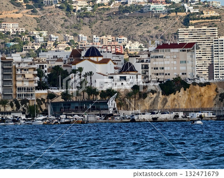 busy waterfront with cafes and ships, vibrant urban port adjacent to rocky cliffs with activities 132471679