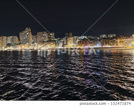 luminous skyline with diverse architecture reflected in tranquil waters during lively nocturnal 132471874