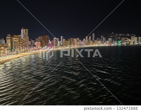 dusk along coast highlighting vibrant urban glow and reflective waves for editorial imagery 132471888