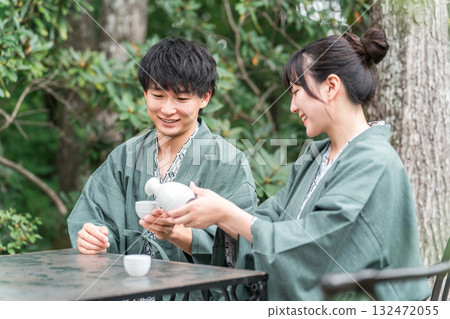 一對穿著浴衣的夫婦在傳統日式旅館的花園露臺上喝清酒 132472055