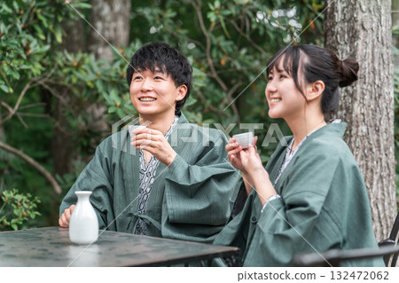 一對穿著浴衣的夫婦在傳統日式旅館的花園露臺上喝清酒 132472062