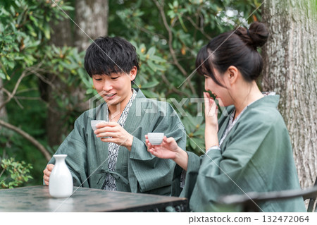 一對穿著浴衣的夫婦在傳統日式旅館的花園露臺上喝清酒 132472064