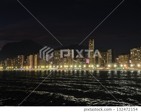 harbor evening scene, vivid coastal panorama with glowing promenade and mountain background at night harbor evening scene, vivid coastal panorama with glowing promenade and mountain background at night 132472154