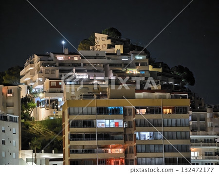 nighttime view of illuminated apartment terraces overlooking bustling waterfront skyline on coastal nighttime view of illuminated apartment terraces overlooking bustling waterfront skyline on coastal 132472177