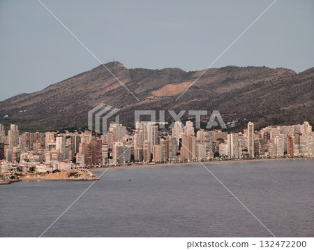 coastal mountain scene, mountains and water surround lively city at dusk with illuminated buildings coastal mountain scene, mountains and water surround lively city at dusk with illuminated buildings 132472200