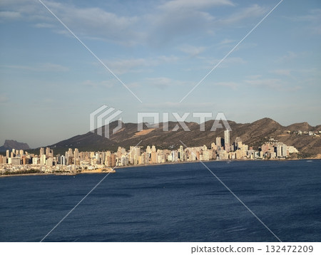 peaceful coastal skyline with urban structures and distant mountain ridges under clear sky 132472209