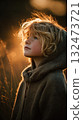 Young child with blonde hair and freckles looks up thoughtfully in warm nature light embracing peaceful lifestyle moment in cozy hooded sweater 132473721