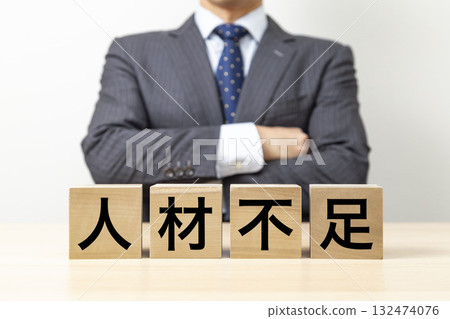 一名商人交叉雙臂,身後是一塊寫著「缺乏人力資源」的方塊 一名商人交叉雙臂,身後是一塊寫著「缺乏人力資源」的方塊 132474076