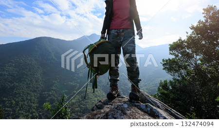 Successful hiker stand on sunrise mountain top cliff edge 132474094