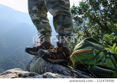 Successful hiker stand on sunrise mountain top cliff edge 132474096