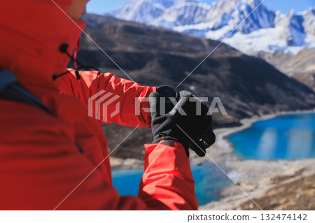 Backpacking woman set the sports watch on high altitude mountain top 132474142