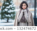 A woman with a beige coat and scarf draped over her shoulders 132474672
