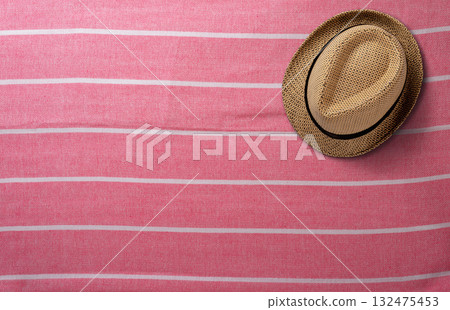 Stylish Straw Hat Resting on a Pink Striped Beach Towel. File with Clipping Path. 132475453