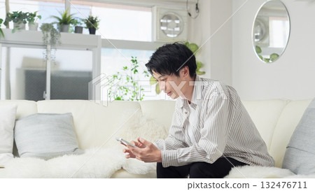 Asian man looking at smartphone in living room 132476711