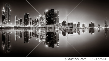 Urban city skyline with illuminated skyscrapers and waterfront railing in black and white at night, Dubai Marina bay UAE 132477581