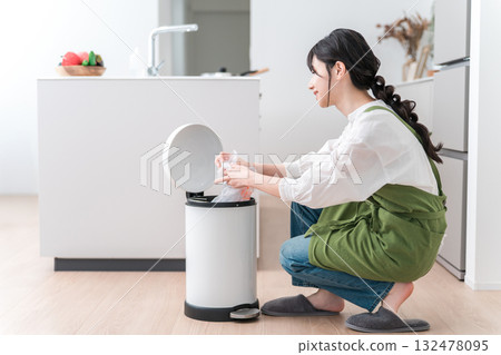 一名繫著圍裙的婦女在廚房的垃圾桶裡收集垃圾,一名家庭主婦 一名繫著圍裙的婦女在廚房的垃圾桶裡收集垃圾,一名家庭主婦 132478095