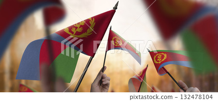 Eritrea flags in their hands on a blurred urban background Eritrea flags in their hands on a blurred urban background 132478104