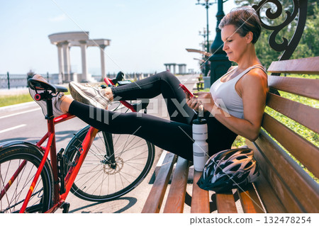 Senior Woman Using Smartphone While Relaxing on Bench with Bicycle on Sunny Summer Day Senior Woman Using Smartphone While Relaxing on Bench with Bicycle on Sunny Summer Day 132478254