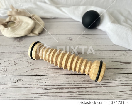 Foot care products: wooden rollers, black balls, and ballet shoes are placed on the shabby floor. Foot care products: wooden rollers, black balls, and ballet shoes are placed on the shabby floor. 132478334