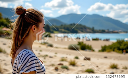 A person is standing on a sandy beach, gazing out towards the water A person is standing on a sandy beach, gazing out towards the water 132478695