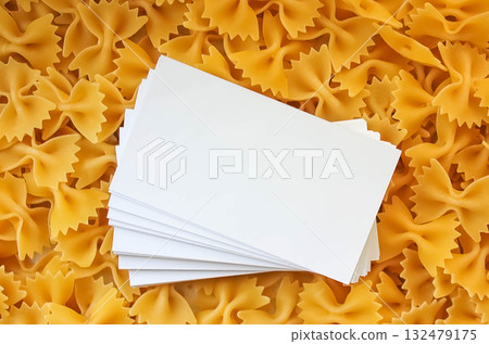 Uncooked pasta scattered in the background. Place for text. Pasta made from durum wheat. Pasta bows Uncooked pasta scattered in the background. Place for text. Pasta made from durum wheat. Pasta bows 132479175