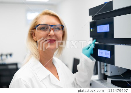 Portrait of scientist next to HPLC system in modern laboratory.  132479497