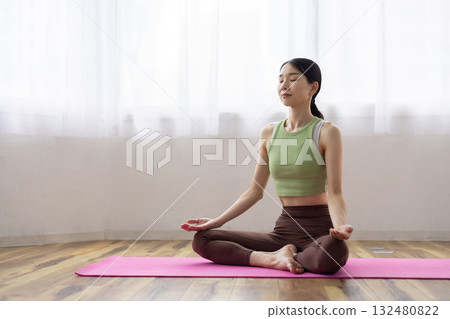 Woman meditating on a yoga mat 132480822