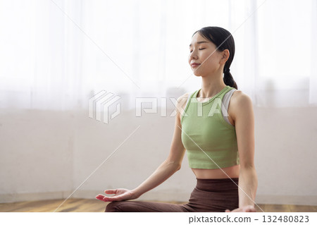 Woman meditating on a yoga mat Woman meditating on a yoga mat 132480823