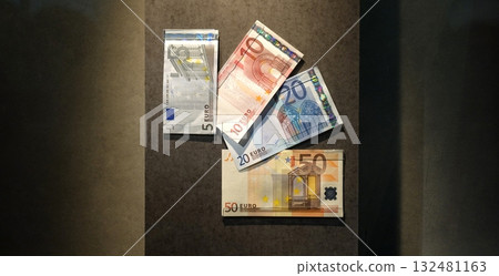 Four euro banknotes on a panel, arranged like playing cards. Four euro banknotes on a panel, arranged like playing cards. 132481163