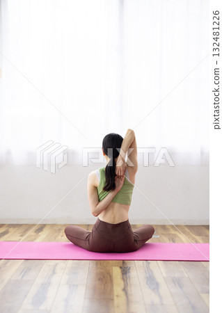 Back view of a woman doing the Cow Face Yoga Pose (Gomukhasana) 132481226