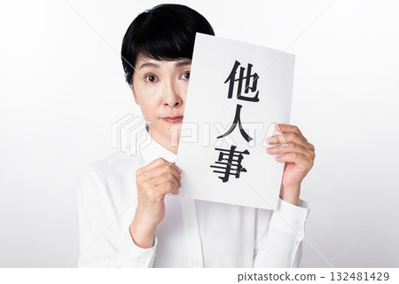 A senior woman looking at the camera and holding a piece of paper that says "It's not my business" 132481429