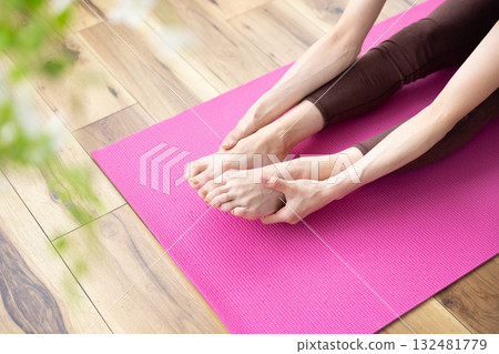 Close-up of a woman's feet and hands stretching on a yoga mat 132481779