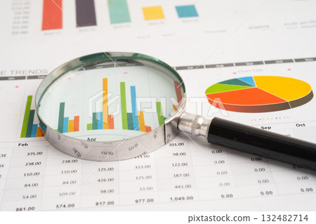 Magnifying glass on spreadsheet and graph paper. Magnifying glass on spreadsheet and graph paper. 132482714