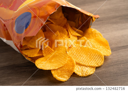 Potato chips, delicious BBQ seasoning spicy for crips, thin slice deep fried snack fast food in open bag. Potato chips, delicious BBQ seasoning spicy for crips, thin slice deep fried snack fast food in open bag. 132482716